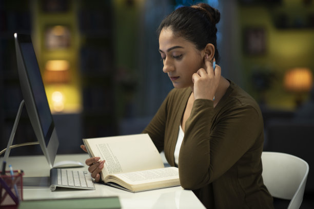 一个年轻的女学生晚上在家看书准备她的考试:-库存照片图片下载