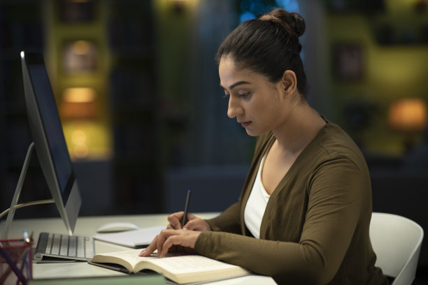 一个年轻的女学生晚上在家准备考试的照片:库存照片图片下载