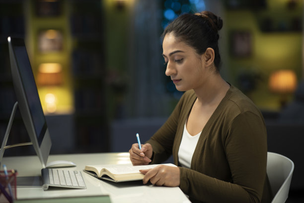 一个年轻的女学生晚上在家看书准备她的考试:-库存照片图片下载