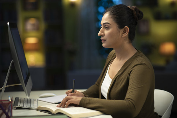 一个年轻的女学生晚上在家准备考试的照片:库存照片图片下载