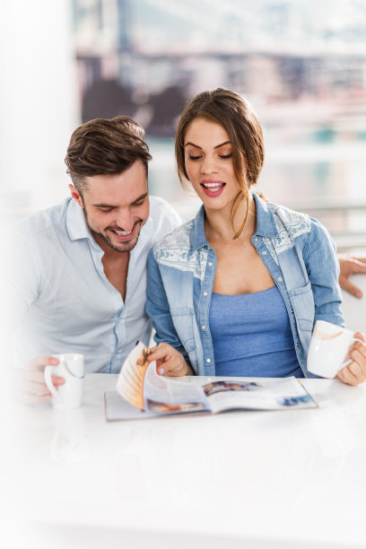 一对在家里看杂志的幸福夫妇。图片下载