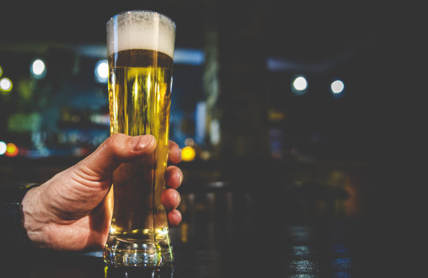 在酒吧里，男人手里拿着一杯啤酒图片下载