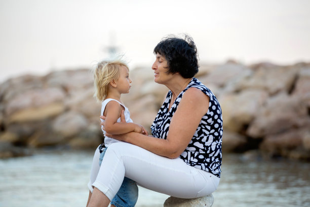 祖母和孩子，可爱的金发男孩和年轻的祖母在沙滩上拥抱图片下载