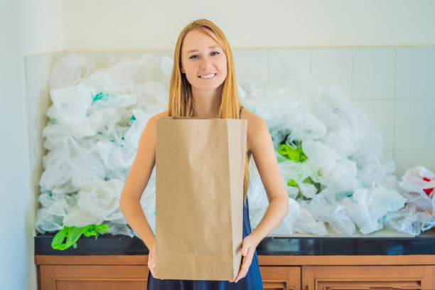 在一堆塑料袋中拿着纸袋的女人。“零浪费”的概念。世界环境日的概念图片下载