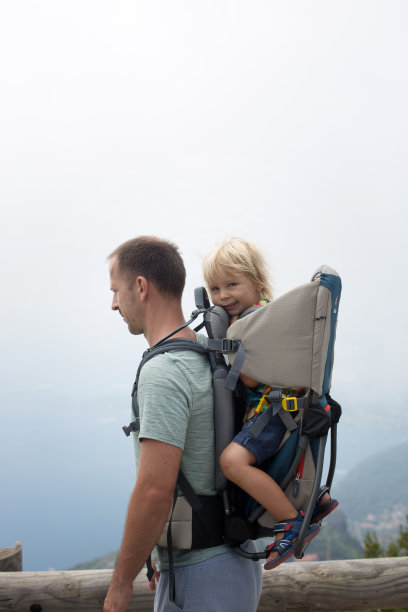 父亲在夏天用背包背他蹒跚学步的儿子图片下载