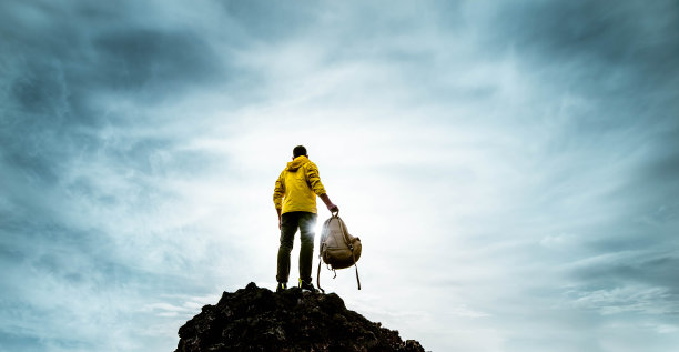 成功的人站在山顶日落-徒步旅行者与背包极限攀登-运动成功和鼓舞人心的概念图片下载