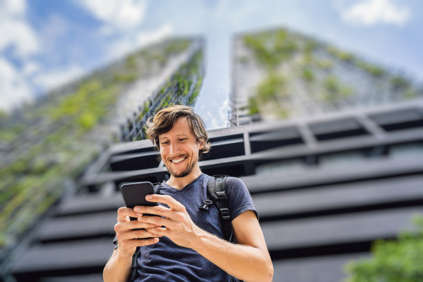 一名男子在摩天大楼的背景下使用智能手机上的地图应用图片下载