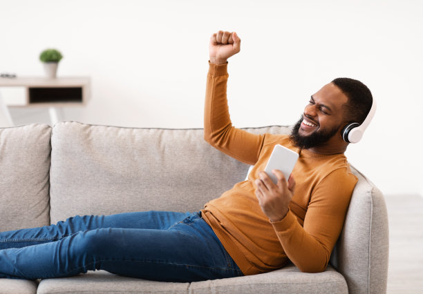 躺在沙发上用智能手机听音乐的男人图片下载