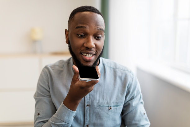 黑人在工作场所使用带有语音助手应用程序的手机图片下载