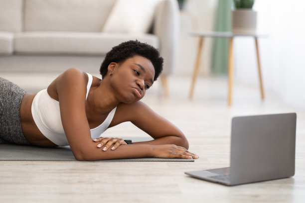 非洲妇女躺在笔记本电脑附近，在室内在线锻炼后疲惫不堪图片下载
