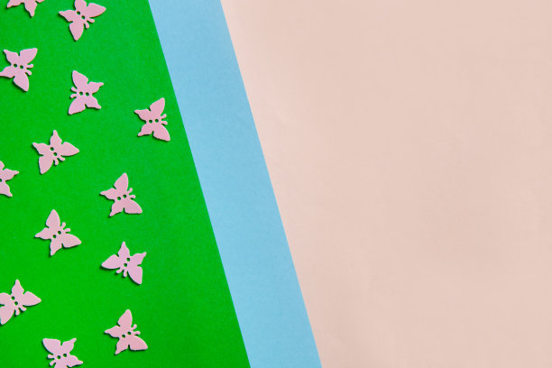 近距离的照片粉红色的蝴蝶在彩色的粉红色，蓝色和绿色的背景上闪闪发光的五彩纸屑。俯视图，春天，复活节和各种节日和事件的概念图片下载