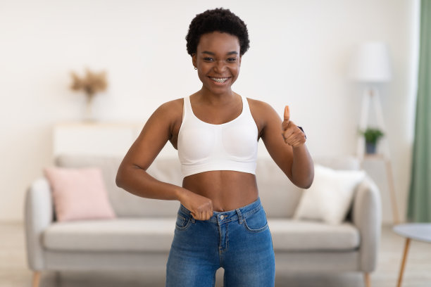 穿着小牛仔裤的瘦黑女士站在室内竖起大拇指图片下载