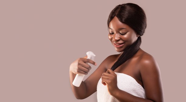 微笑的黑人女士使用保湿发胶，做分叉修复治疗图片下载