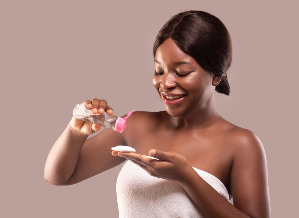 洁面的概念。迷人的黑色女士将胶束水倒在棉垫上图片下载