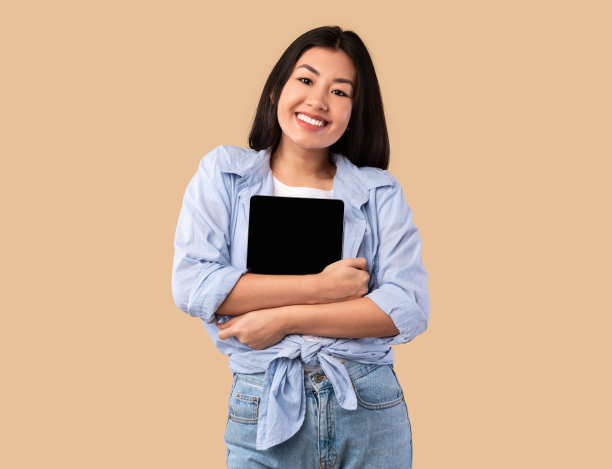 兴奋的亚洲女人拥抱平板电脑在工作室图片下载