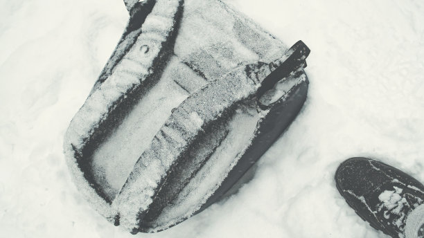 地上有一个被雪覆盖的背包。男人的脚就站在旁边图片下载