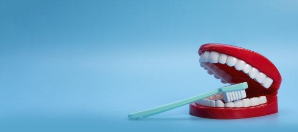 玩具牙刷和牙齿，红色的牙龈，蓝色的背景。牙齿的健康概念。图片下载
