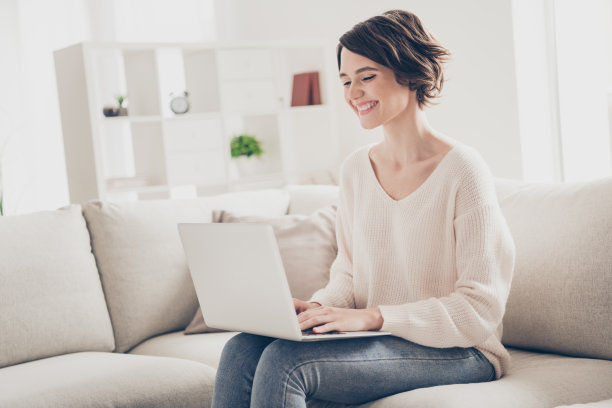 开心的波波头女人的侧面照片，拿着笔记本电脑，坐在沙发里，在屋里笑好心情图片下载