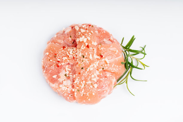 生汉堡，肉丸在白色的背景。在家吃快餐。方便食品、预煮。生鸡肉汉堡在一个白色的背景迷迭香枝。即时的肉。烤汉堡。图片下载