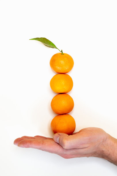 男手捧着堆在一起的橘子孤立在白色。健康饮食。极简主义和平衡的概念图片下载