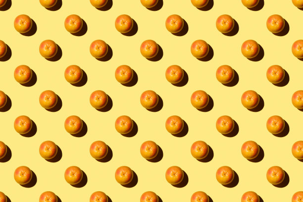 时尚的图案与新鲜的水果在明亮的淡黄色的背景。以彩色纸为背景的简约风格。彩色照片。平的。最小的创意概念。食品的背景。切片葡萄柚图片下载