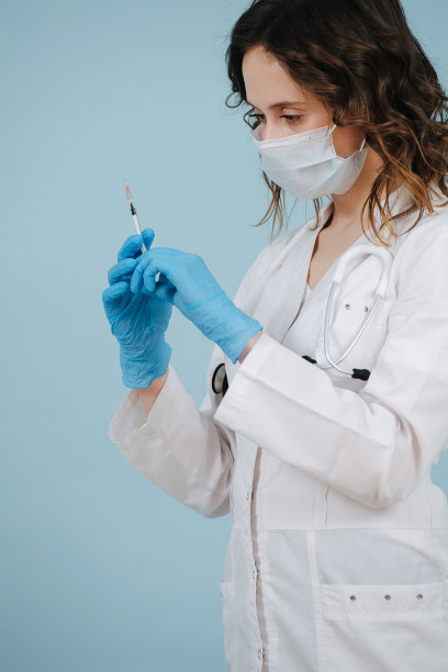 重症护士用力挤出注射器注射疫苗。在蓝色背景。图片下载