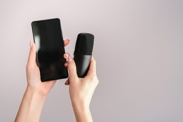 Clubhouse Drop-in音频的概念是一个声控的社交媒体应用程序。智能手机和麦克风在一个灯光背景的女性手中图片下载