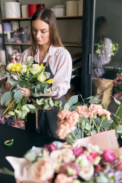 成功的现代花店的照片，穿着围裙制作花的图片，在现代室内花店创造美丽的花束不同的色彩图片下载
