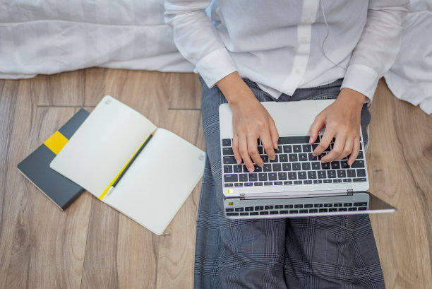 年轻的亚洲女子躺在家里的床上做笔记和工作笔记本电脑。图片下载