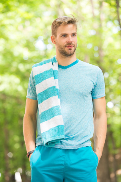 需要休息一下。男子运动员在户外用毛巾跑步后，自然背景。运动员在公园里训练。运动员穿着运动服和毛巾训练。跑步锻炼，休息放松图片下载