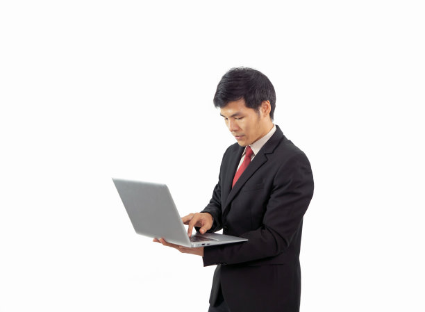 一个年轻的亚洲商人站着，拿着手提电脑，手提电脑在白色背景上孤立的科技设备。人们的生活方式。图片下载