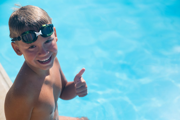 快乐男孩带着护目镜在游泳池里积极的生活方式图片下载