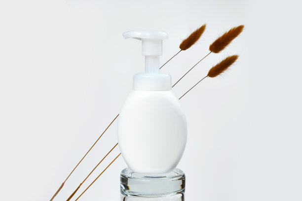 玻璃基座上的白色无商标泵瓶和棕色草药Lagurus。装乳液、乳霜、防晒霜、洗发水或护发素的空白容器。样板造型，化妆品广告。极简主义。图片下载