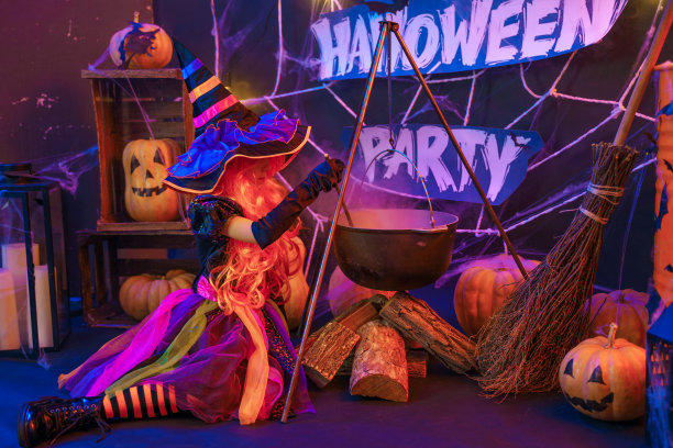 穿着女巫服装的美丽小女孩在室内用南瓜庆祝万圣节快乐派对图片下载