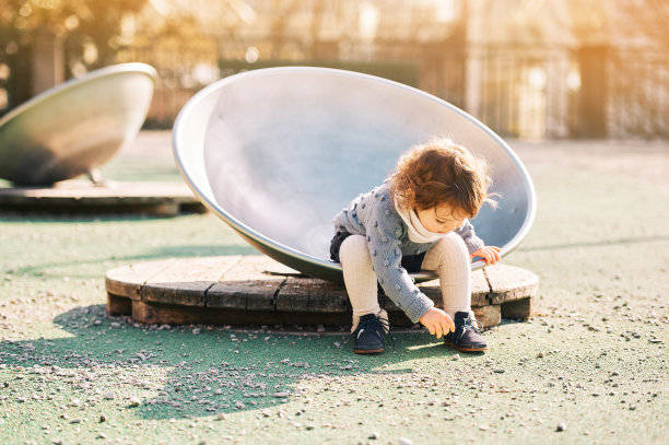 户外肖像可爱的蹒跚学步的女孩在操场上玩，1 - 2岁的孩子在公园玩图片下载