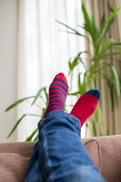 穿着红袜子，双腿交叉躺在沙发上。图片下载