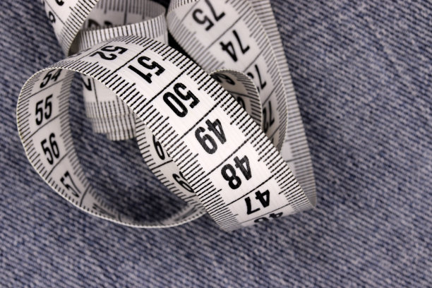 蓝色牛仔背景上的卷尺图片下载