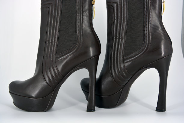 棕色性感时尚的女性秋靴带有宽口胶，自然光滑。女式鞋上有一个高而薄的发夹，白色背景上有一个宽平台，鞋跟上有拉链。图片下载