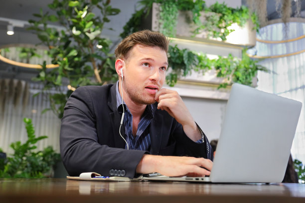 白人商人正在使用视频通话，同时在绿色环保的现代工作场所周围的空气净化侯图片下载