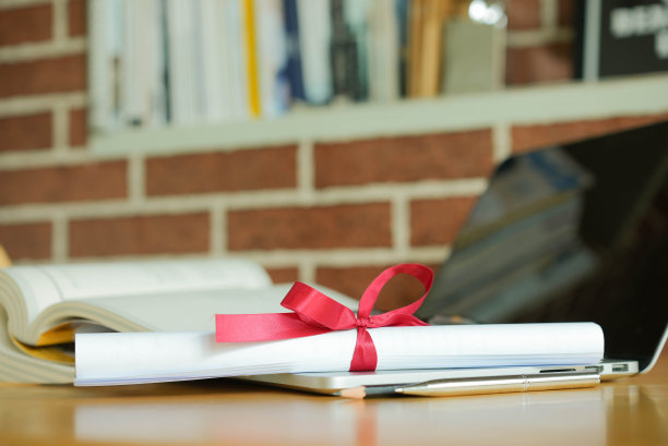 将学士学位证书放在笔记本电脑上，与图书馆的书籍一起在线学习毕业概念图片下载