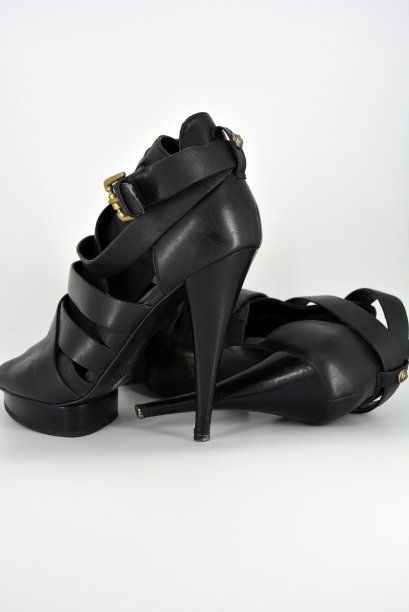 白色背景上的细高跟鞋上的黑色凉鞋。用真皮制成的时髦女鞋。漂亮的金色鞋垫和扭皮缎带的晚装凉鞋。图片下载