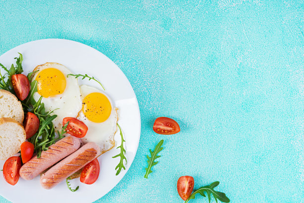 英式早餐-煎蛋，香肠，西红柿和新鲜芝麻菜。美国的食物。俯视图，平放图片下载