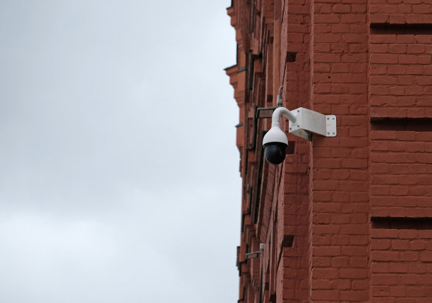 实时现代在线安全监控系统闭路电视摄像头。安装在砖墙建筑上的室外监控摄像头。设备系统的安全、寿命或资产服务。图片下载