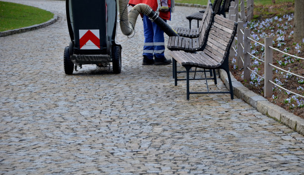 金属长凳排成一排的广场。广场上铺着灰色的花岗岩立方体。用吸尘器清扫公园里的粪便，用长管用软管吸烟叶和烟头图片下载