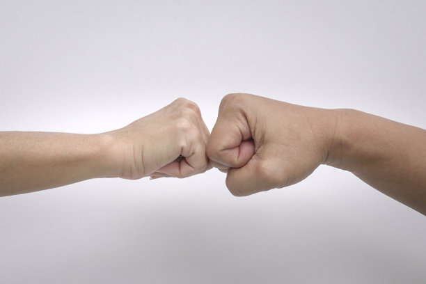 一个男人和女人的手在白色背景下的拳头撞击的特写。图片下载