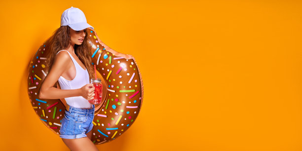年轻女子女孩摆姿势与甜甜圈形状的游泳充气圈孤立在黄色背景图片下载