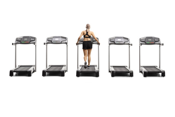 一名年轻女子在跑步机上行走，周围都是空的跑步机图片下载