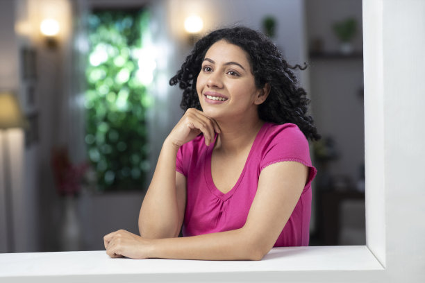 一个年轻女子站在窗户和阳台附近的照片:库存照片图片下载