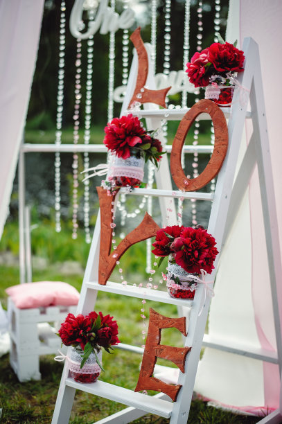 装饰用的情书和红色的牡丹花插在一个玻璃花瓶上，放在木架上。为婚礼和情人节拍照的地方。美丽时尚的户外照片区。图片下载