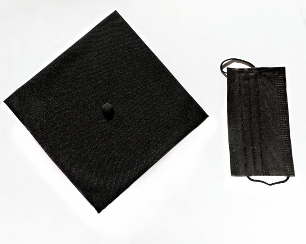 毕业生戴着黑色的帽子和防护口罩，戴着白色的背景，学习时保护自己不受病毒感染，新常态图片下载